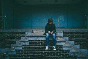 Boy sitting on stairs contacting someone to help him