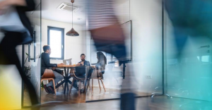 Three people sitting around a round table in a meeting room