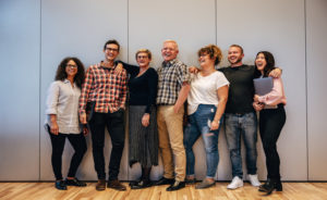 A group of Caucasian females and males laughing leaning against a wall at a DISC workshop