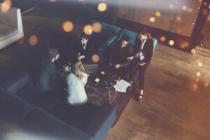 Startup team. Meeting on the couch. Big open space office. Five people. Intentional lens flares