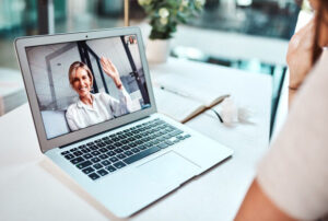 An Employee Assistance Program psychologist on a video conferencing waving hello to an employee who is upset.